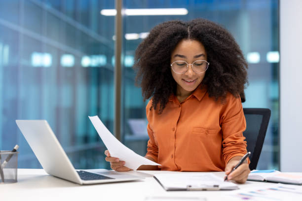 istock Young businesswoman working diligently at her desk with documents in hand 2190034046