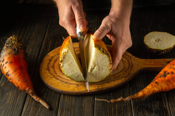 istock Two hands expertly cut a vibrant orange beet vegetable on a wooden board surrounded by other freshly harvested produce. The warm kitchen ambiance highlights the rich textures 2190037349
