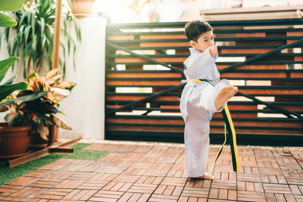 istock boy practicing taekwondo high kick in the air. 2190038466