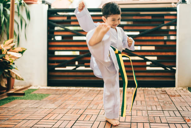 istock boy practicing taekwondo high kick in the air. 2190038483