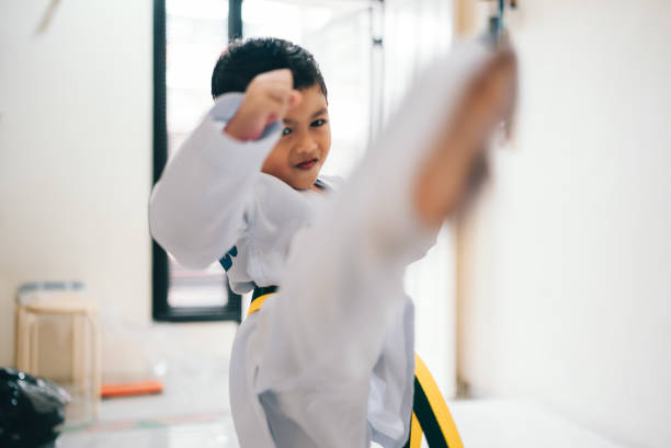 boy practicing taekwondo high kick in the air.