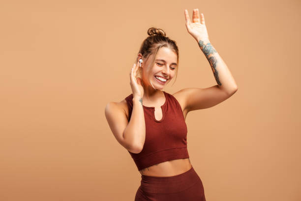 istock Happy young fit female instructor dancing holding hands up, using headphones in studio 2190040547