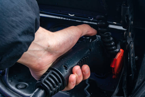 istock Individual uses foot to stabilize a connection while working on an electrical device in wet weather conditions 2190044645