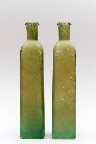 istock two tall green glass bottles with a rustic, weathered finish, displayed against a plain white background 2190048205