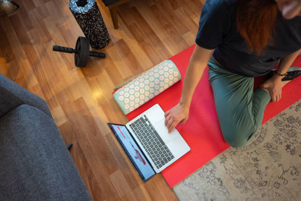 istock Woman on yoga mat taking online exercise class at home 2190053611