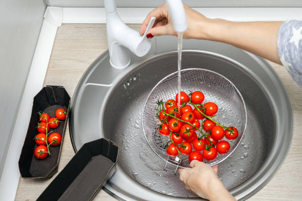 istock woman washing tomatoes in a colander in the kitchen. 2190060447