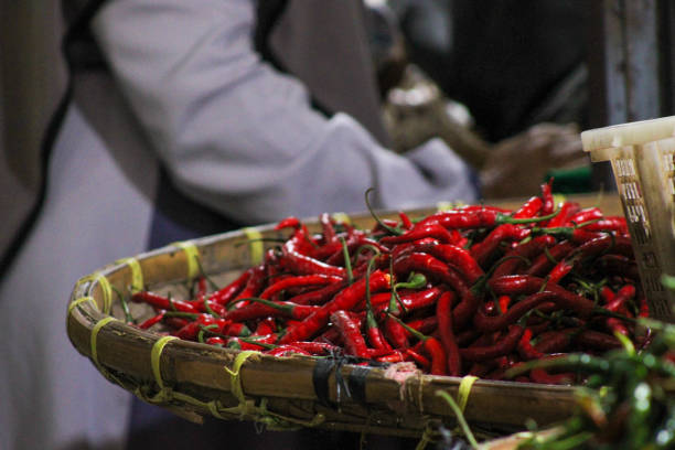 A vibrant close up shot of fresh, red chilies displayed at a bustling traditional market. These chilies are perfect for adding a spicy kick to any dish, showcasing their vibrant color and natural texture. The image captures the essence of local markets, where fresh produce like these chilies is readily available. Ideal for food related projects, this image evokes the freshness, richness, and warmth of authentic culinary experiences, making it perfect for websites, blogs, and advertisements focused on food, cooking, and healthy living.