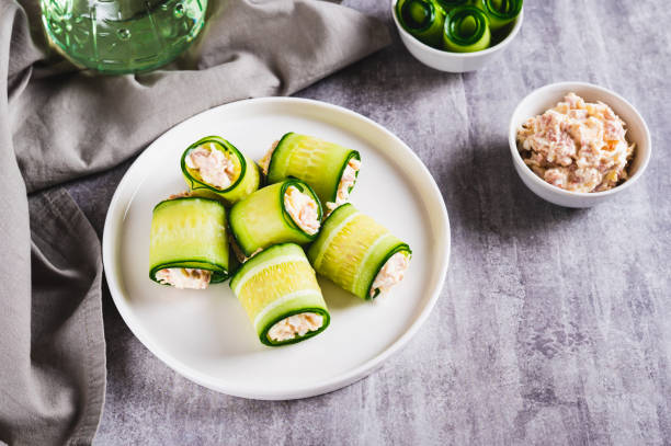 istock Cucumber rolls with fish salad on a plate on the table 2190067754