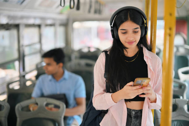istock Young woman with headset, looking at her phone on a bus 2190075168