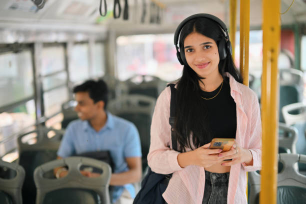 istock Young woman student with her headset on, commuting on a bus and smiling at the camera 2190075178