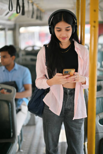 istock Young woman student standing with her headset on and commuting on a bus 2190075189