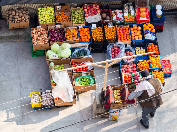 Yerevan, Armenia - December 7, 2024: top view of local fresh vegetables and fruits stall with seller in city courtyard in winter day