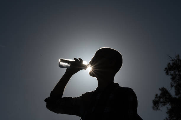 Thirsty man on a mountain hike, carrying a water bottle and drinking.