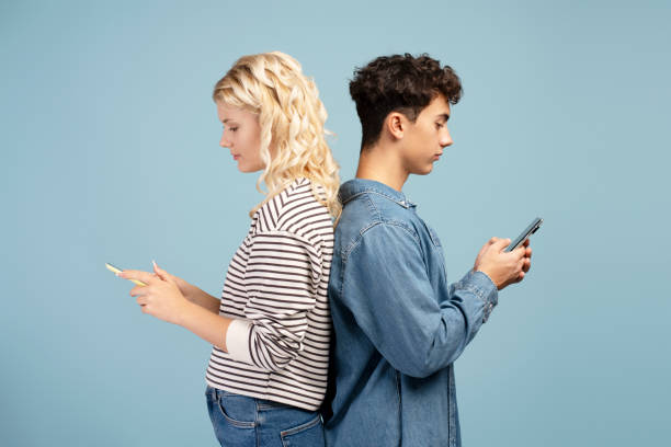 Portrait of attractive friends, holding mobile phone, standing back to back, using mobile app