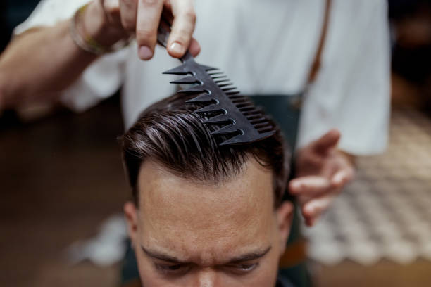 Barber precisely trim a male clients hair, creating clean lines and a polished look. The client remains calm and focused, enjoying a premium grooming session in a modern barbershop