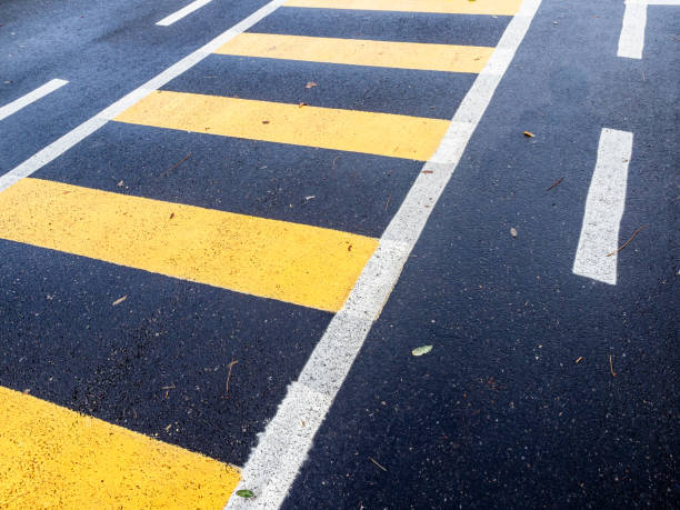 istock yellow painted footpath on black asphalt road 2190082653