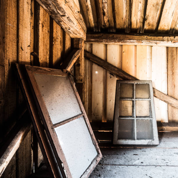 Old wooden windows leaning against the wall in a rustic barn interior with soft natural light