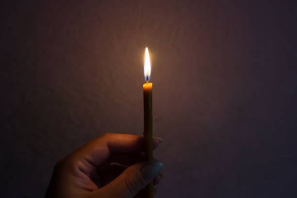 istock hand with a candle in the dark.close-up 2190090047