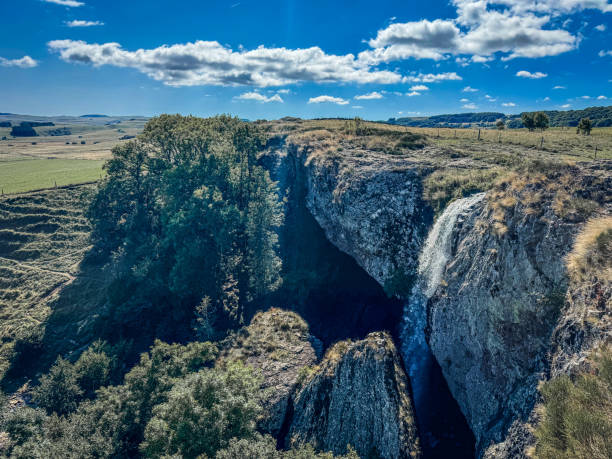 istock Cascade du Deroc, waterfall is cascading from a rocky cliff overlooking a green valley under a blue sky 2190092686