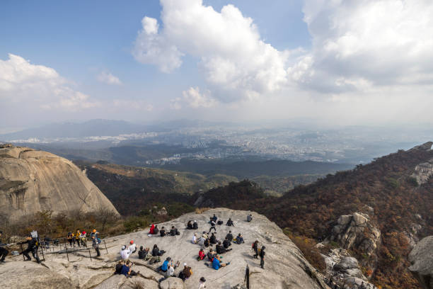 seoul, south korea - october 23, 2023: people hiking and climbing to baegundae mountain and resting at the peak in bukhansan national park in seoul.