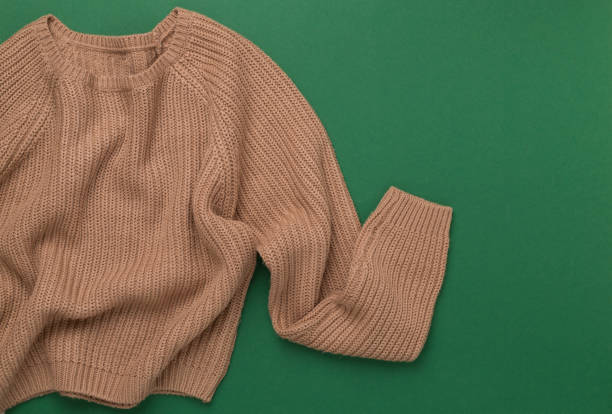 istock Beige knitted sweater on color background, top view 2190096007