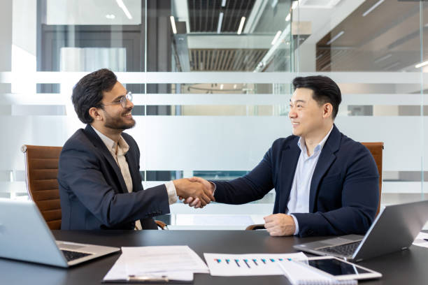 istock Business professionals shaking hands in a modern office environment 2190097977
