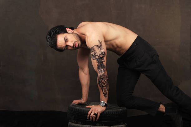 Portait of a young stylish Pakistani male model with tyres and tattoo on hands