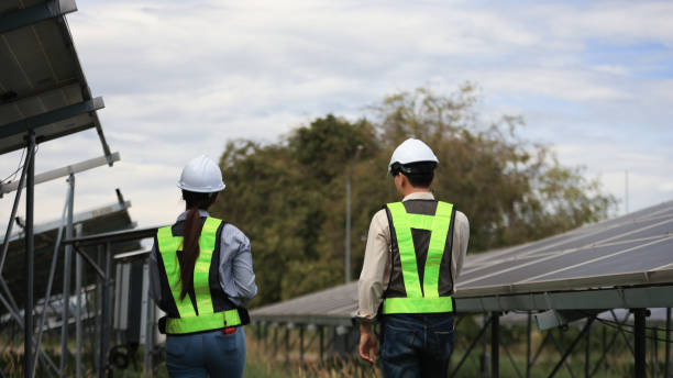 istock Back view of Man Solar Installer and Woman Environmental Engineer controlling process of building of new industrial solar energy farms. 2190100384