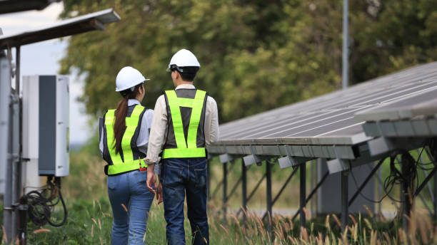 istock Back view of Man Solar Installer and Woman Environmental Engineer controlling process of building of new industrial solar energy farms. 2190100388