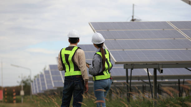 istock Back view of Man Solar Installer and Woman Environmental Engineer controlling process of building of new industrial solar energy farms. 2190100391