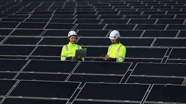 The solar project engineers team  working on laptops and  drawing  on-site  at the solar panel farm, sustainable green renewable energy, Zero Carbon Credit