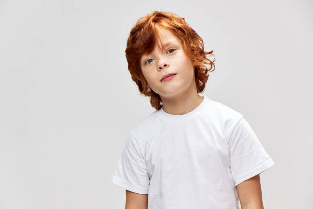 istock Red haired child in a white t-shirt tilted his head to one side red 2190103615