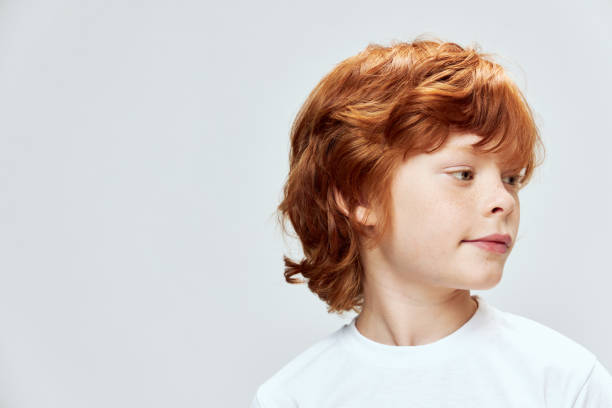 istock Red-haired boy face close-up head turned on the side close-up gray background 2190104278