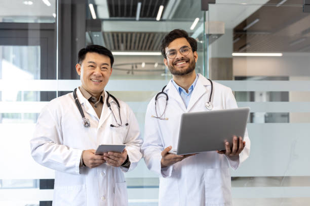 istock Two doctors standing confidently in modern medical office with laptop and tablet, showcasing digital healthcare collaboration and teamwork. Ideal for representing professional medical environment. 2190106109