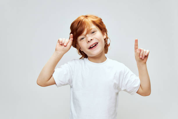 istock boy with red hair gestures with his hands and index finger up. Copy Space 2190107352