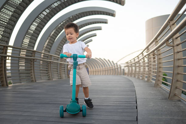 Multiracial Toddler Riding a Blue Three-Wheeled Scooter on a Modern Bridge