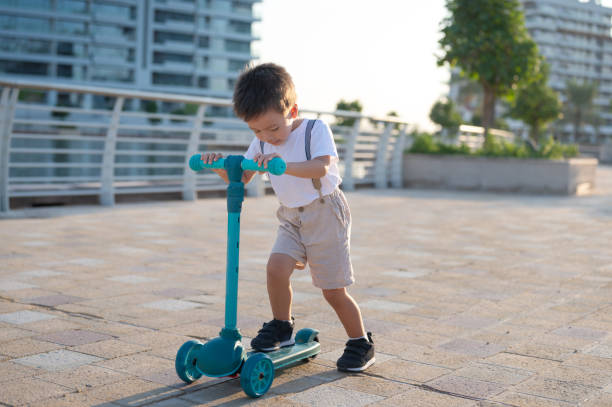 istock Toddler Riding a Blue Three-Wheeled Scooter Outdoors 2190108239