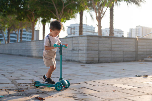 istock Toddler Riding a Blue Three-Wheeled Scooter Outdoors 2190108257