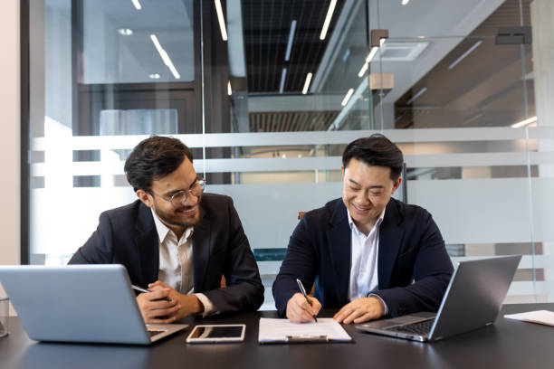 istock Two businessmen signing a document together in a modern office setting 2190108773