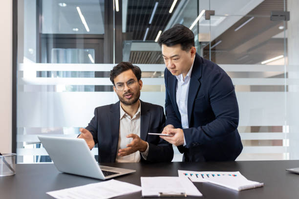 istock Two business professionals in a modern office setting analyzing data on a laptop and smartphone, collaborating effectively on a project for successful business outcomes 2190109582