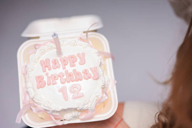 Fluffy birthday cake with a candle on pink and soft balloon surface.
