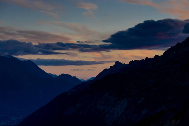 Scenic view of mountain ranges against cloudy sky during sunrise.
