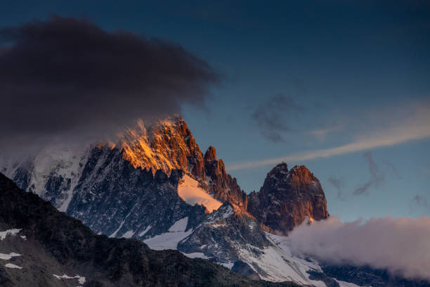 istock Sunset in the mountains. Red light on the sky with some clouds above the stunning mountain peaks and snow summits of the Alps 2190120409