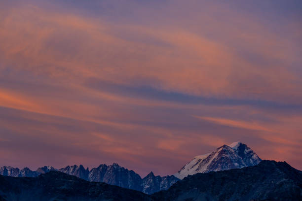istock Sunset in the mountains. Red light on the sky with some clouds above the stunning mountain peaks and snow summits of the Alps 2190120626