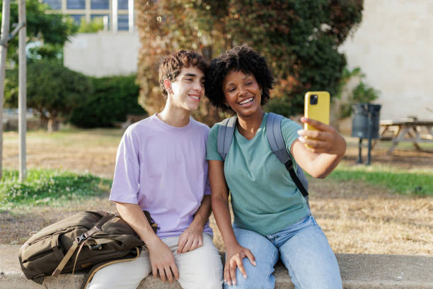 istock Smiling students taking selfie with smartphone outdoors 2190121144