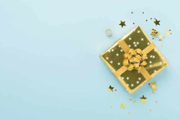 istock Golden gift boxes and confetti on color background, top view 2190121307