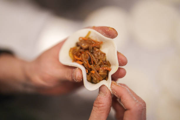 Filling and folding Korean dumplings with rice noodles - dangmyeon.