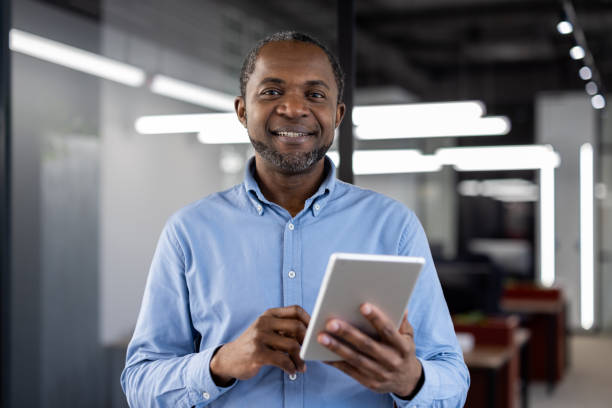 istock Confident african american businessman using a digital tablet in a modern office environment, showcasing technology and business expertise with a professional and approachable demeanor. 2190123457