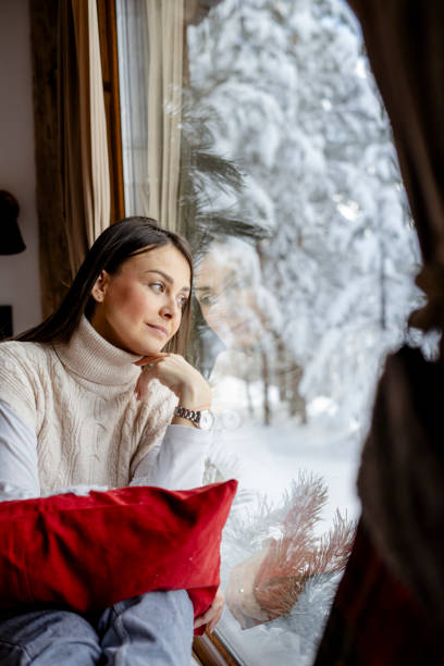 istock Beautiful woman relaxing by the window in forest cabin 2190124270