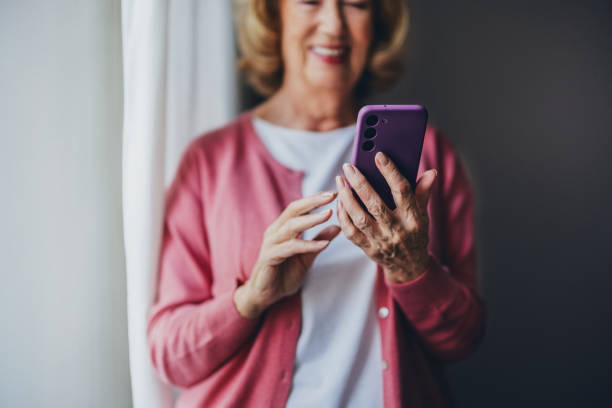 istock Smiling Senior Woman Using a Smartphone by a Bright Window 2190128590